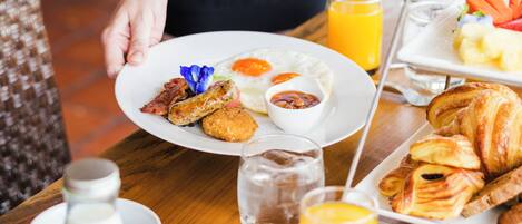 Una bandeja de desayuno con huevos, tocino, cruasanes y un vaso de jugo de naranja.