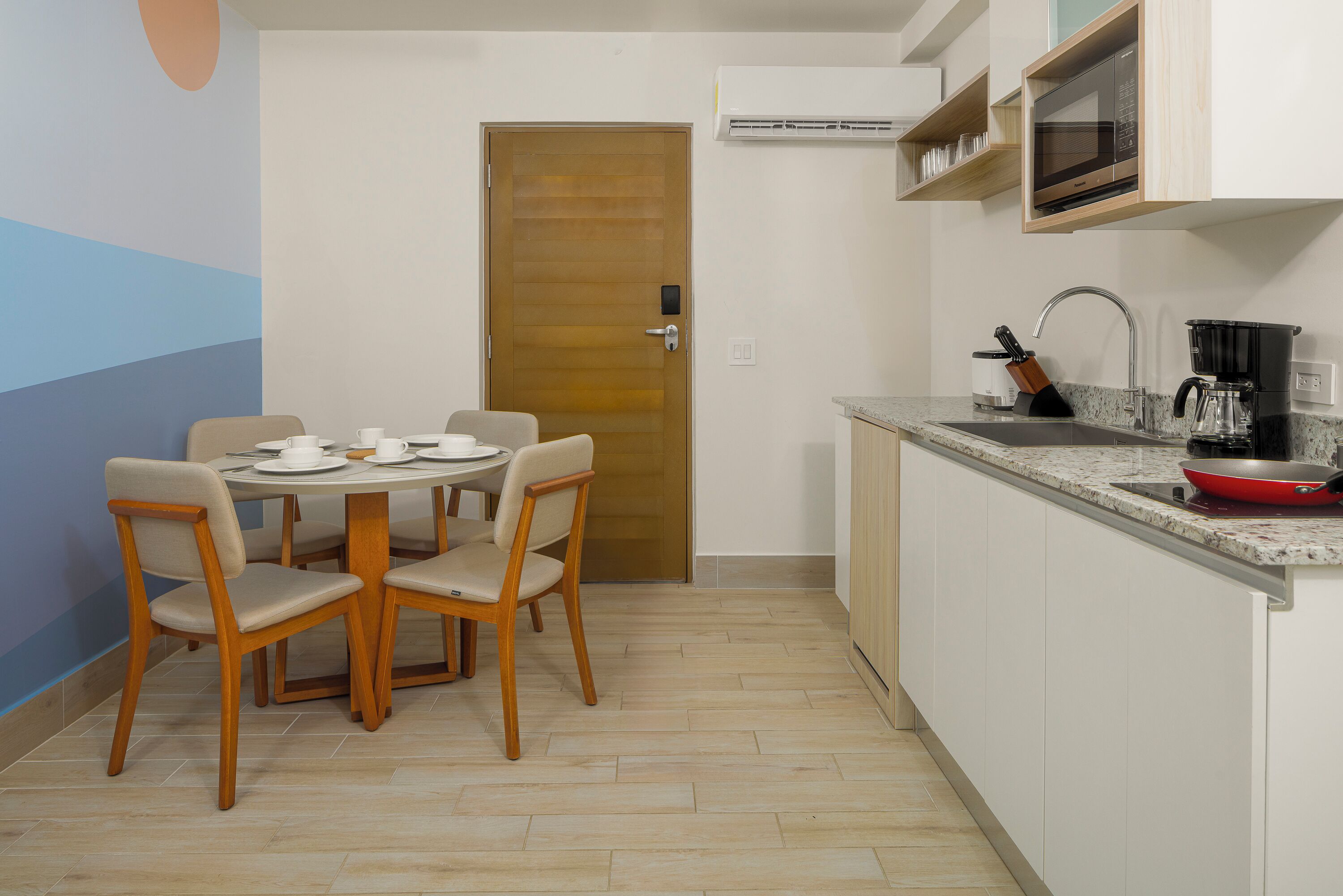 A compact kitchen with a dining area, a microwave, a coffee maker, and a sink.