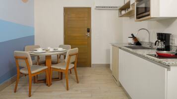 A compact kitchen with a dining area, a microwave, a coffee maker, and a sink.