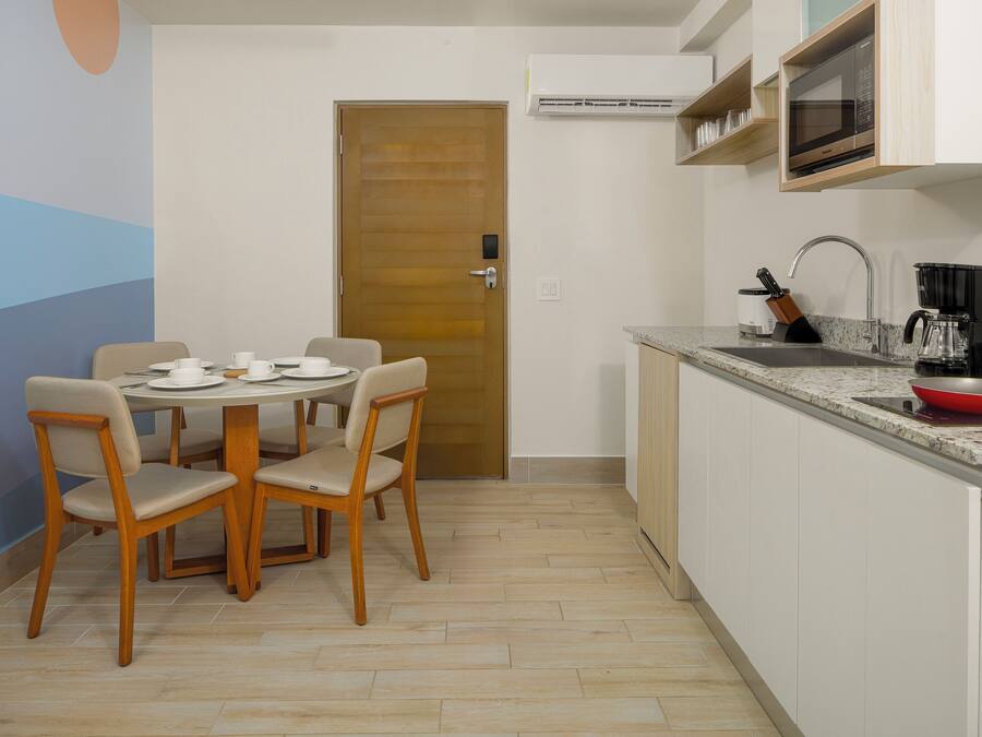 A compact kitchen with a dining area, a microwave, a coffee maker, and a sink.