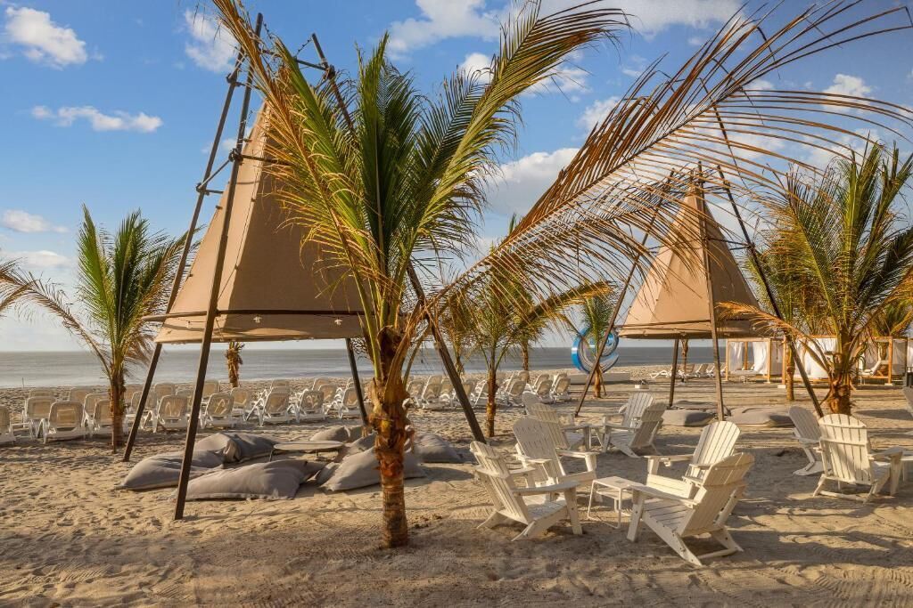 Una spiaggia con lettini bianchi e palme.