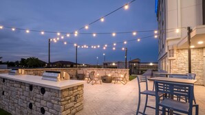 An outdoor patio area with stone walls, seating, and string lights. - Everhome Suites Amarillo West - Medical Center (Amarillo)