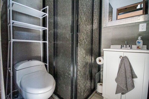 Une salle de bain avec des toilettes blanches, un porte-serviettes et un lavabo avec un miroir au-dessus.