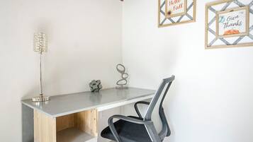 A small office space with a desk, chair, and two wall decorations.