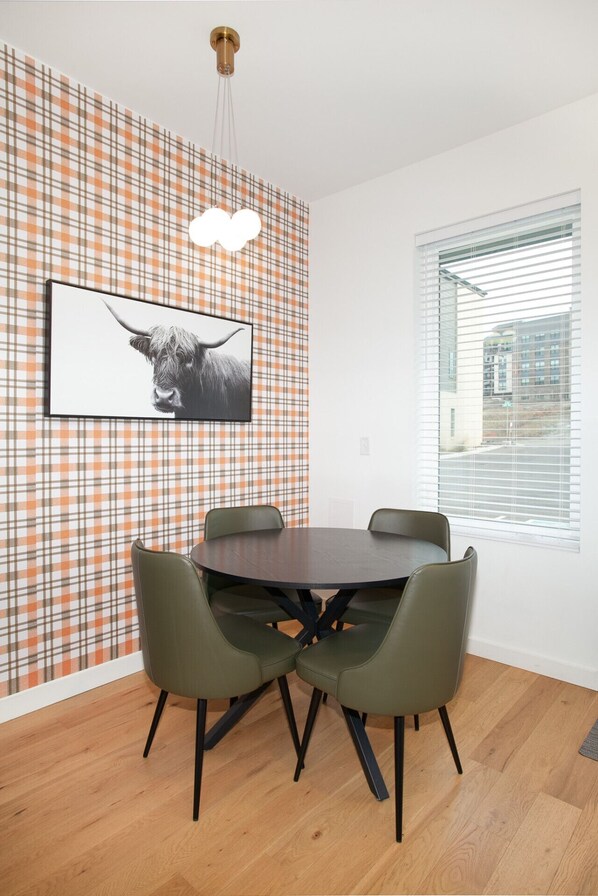 A dining area with a plaid-patterned wall, a round table, and four chairs.
