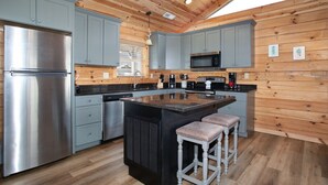 Une cuisine moderne avec des meubles gris, des appareils en acier inoxydable et un îlot central doté de tabourets.