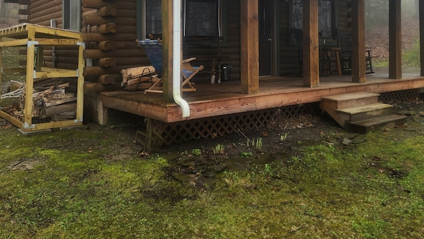 A log cabin with a porch, a covered outdoor seating area, and a visible chimney.