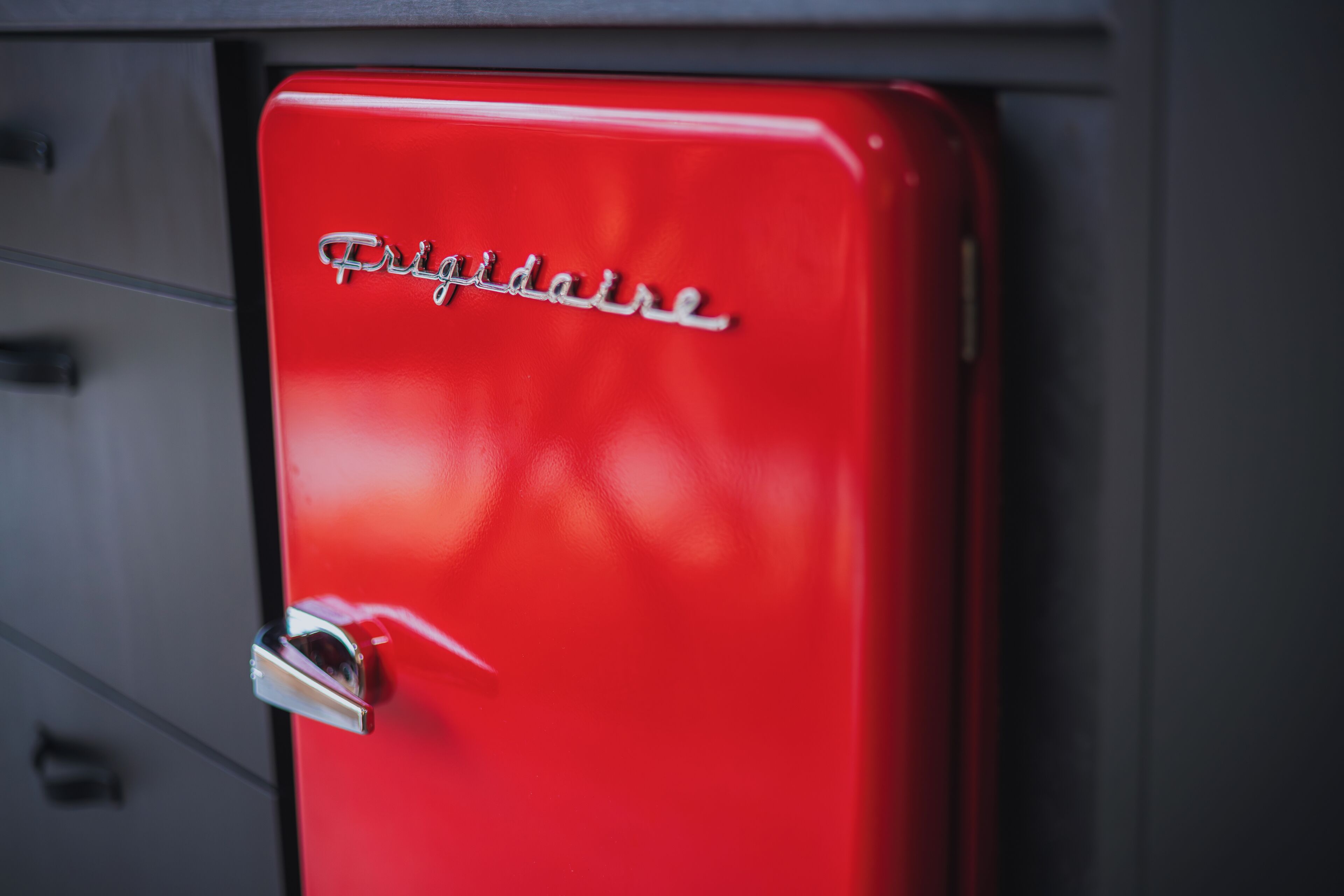 Een rode Frigidaire koelkast met een chroom handvat en een metalen embleem.