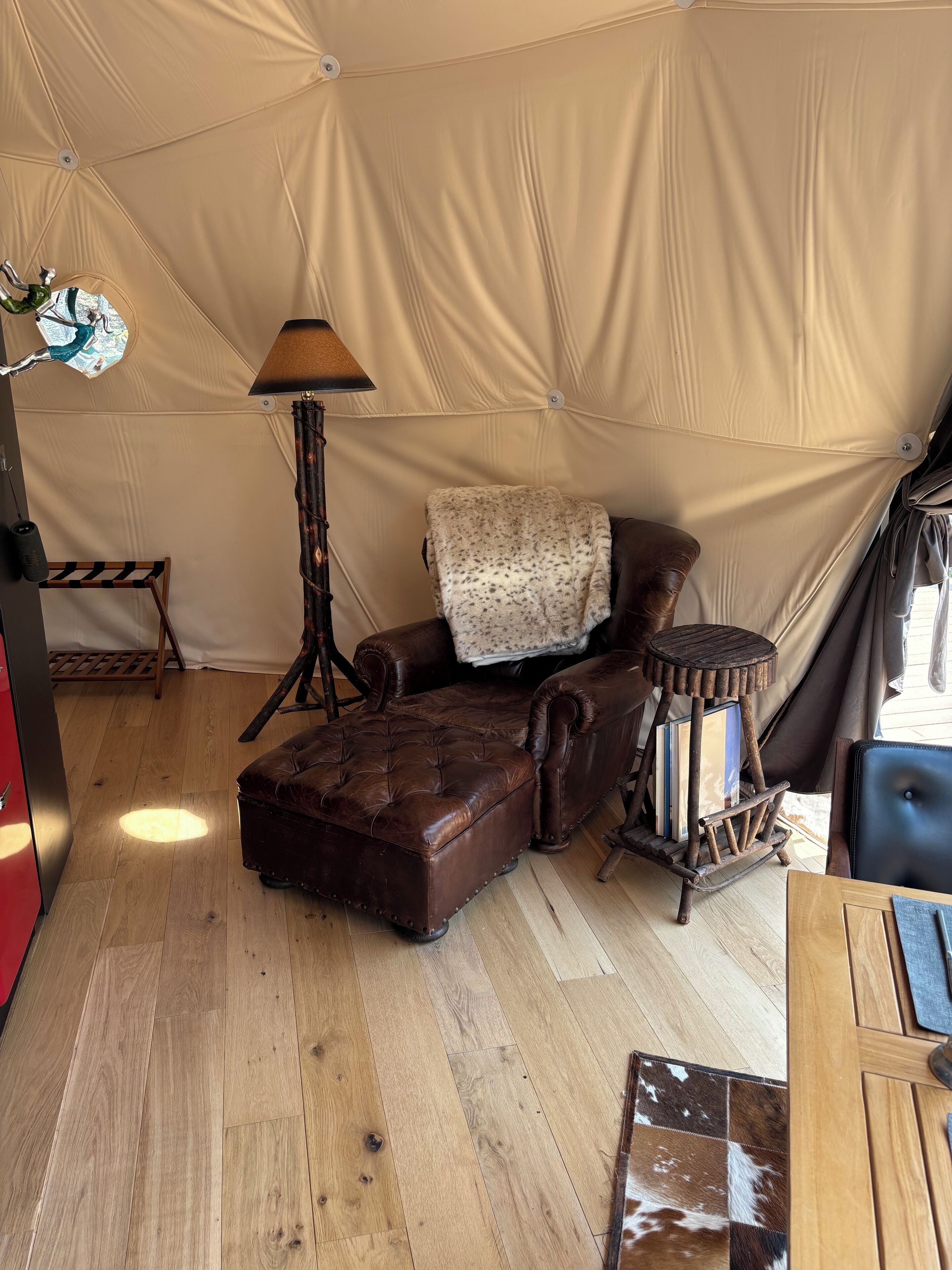 Ein Zeltinneres mit Ledersessel, Lampe, kleinem Tisch und einem gemusterten Teppich.