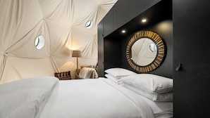 A modern bedroom with a large bed, a round mirror, and a unique tent-like ceiling structure. - Domes at Catskills (Swan Lake)