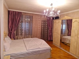 Een slaapkamer met een groot bed, een kroonluchter en een garderobe met spiegel.