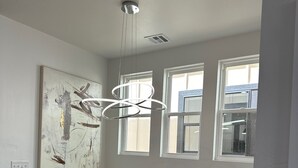 Quarto moderno com mesa preta, bancos brancos, uma grande pintura abstrata e um lustre de design exclusivo.