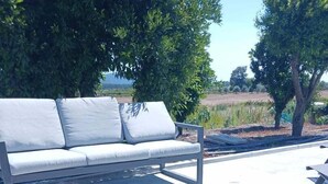 An outdoor dining area with a table set for a meal, a couch, and trees in the background.