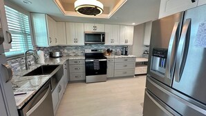 A modern kitchen with stainless steel appliances, a central island, and a built-in microwave.