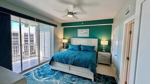 A bedroom with a bed, two bedside tables, a ceiling fan, and a view of the outside through a sliding door.