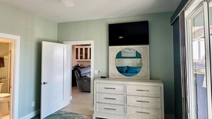 A hallway with a white dresser, a mirror with a decorative frame, and a door leading to a bathroom.