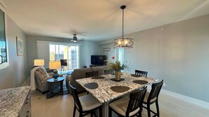 Una sala de estar moderna con una mesa de comedor, sofá y televisor.