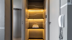 A narrow, well-lit hallway with a telephone on the wall, a towel on a shelf, and a door at the end. - Copan 203e in S o Paulo (São Paulo)