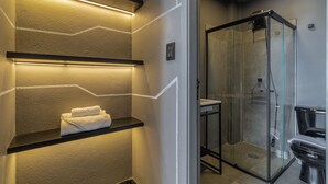 A modern bathroom with a glass shower enclosure, a black toilet, and a towel rack with folded towels. - Copan 203e in S o Paulo (São Paulo)
