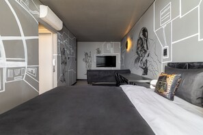 Une chambre d’hôtel moderne équipée d’un grand lit, d’un bureau et d’un téléviseur à écran plat.