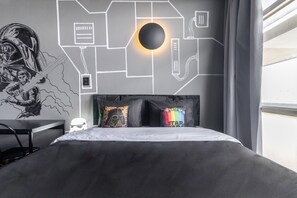 Une chambre moderne avec un lit, des coussins sur le thème de Star Wars et une fresque murale.