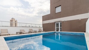 Ein Pool auf dem Dach mit Liegestühlen und Blick auf die Skyline der Stadt.