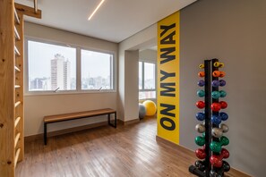 A room with large windows, a bench, and a wall-mounted exercise equipment.
