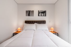 A neatly made bed with white bedding, two wall-mounted artworks, and bedside lamps on wooden nightstands. - Miq277-1107 in S o Paulo (São Paulo)