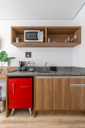 A kitchen with a microwave, coffee maker, and red refrigerator.