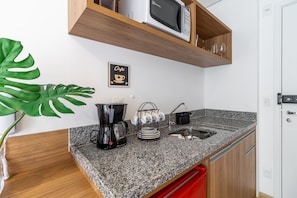 A kitchen with granite countertops, a coffee machine, a sink, and a microwave on a wooden shelf. - Miq277-1107 in S o Paulo (São Paulo)