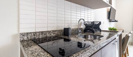 A modern kitchen with a granite countertop, black stove, and stainless steel sink.