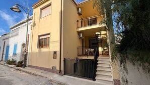 A two-story building with a balcony, a staircase, and a gate. - Casa Amodei 2 a Pochi Passi dal Mare (San Vito Lo Capo)