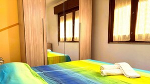 A room with a bed, a mirror, and a window with curtains. - Casa Amodei 2 a Pochi Passi dal Mare (San Vito Lo Capo)