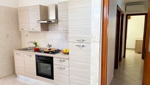 A modern kitchen with a built-in oven, a gas stove, and a stainless steel sink. There are cabinets with wooden handles and a backsplash with hexagonal tiles. - Casa Amodei 2 a Pochi Passi dal Mare (San Vito Lo Capo)