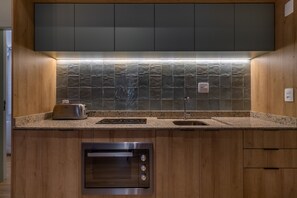 Une cuisine moderne avec des meubles en bois, un four encastré, un grille-pain et un pare-feu en carreaux.
