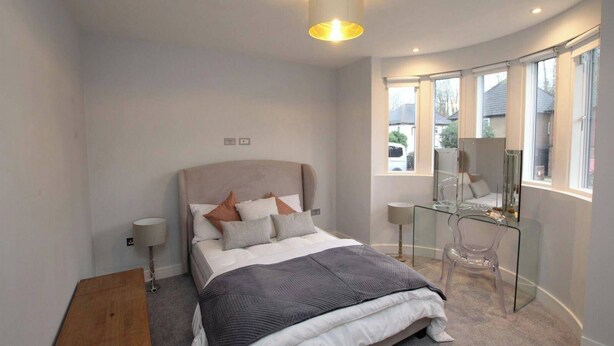 A modern bedroom with a bed, bedside lamps, a glass desk, and a large window. - Essex Luxury Retreat With 6 Bedrooms (Brentwood)