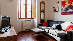 A living room with a sofa, a window, a radiator, a television, and a painting on the wall. - Casa Fiamma in Rome With 1 Bedrooms and 1 Bathrooms (Rome)