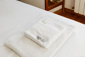 A neatly folded white towel with a bottle of lotion on a white surface, likely a bathroom counter. - Casa Fiamma in Rome With 1 Bedrooms and 1 Bathrooms (Rome)