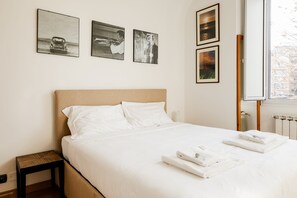 A neatly made bed with white linens and towels, a headboard, and three framed pictures on the wall. - Casa Fiamma in Rome With 1 Bedrooms and 1 Bathrooms (Rome)