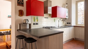 A modern kitchen with a central island, red cabinets, a gas stove, and a window providing natural light. - Casa Fiamma in Rome With 1 Bedrooms and 1 Bathrooms (Rome)