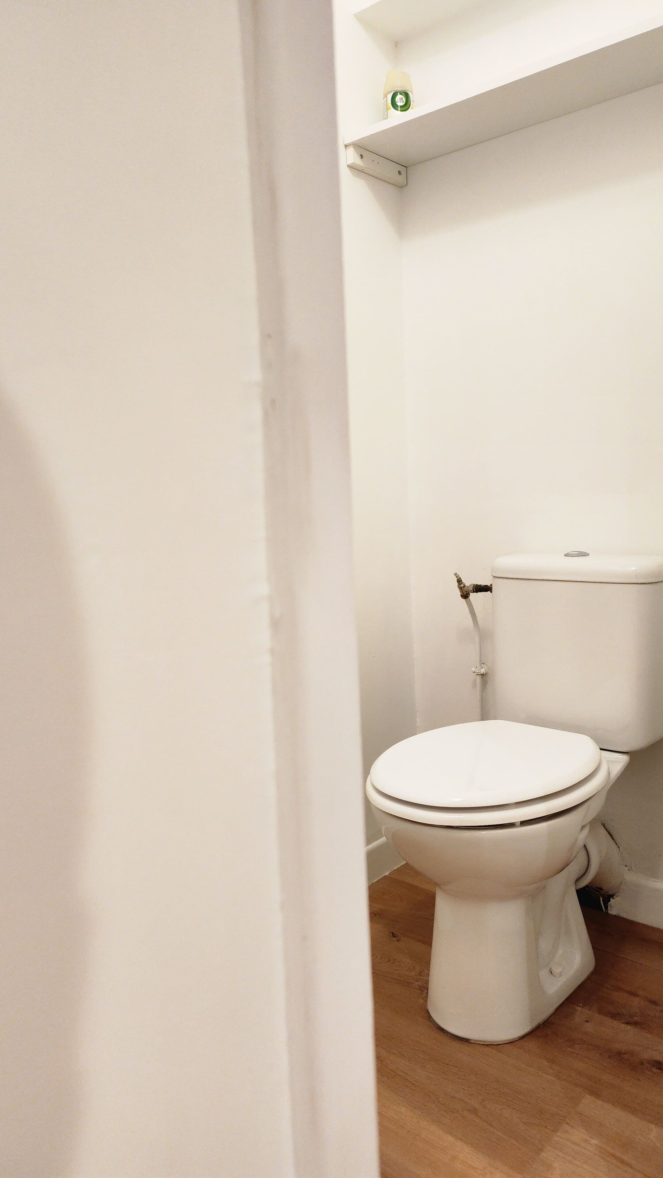 A white toilet in a bathroom with a wooden floor.