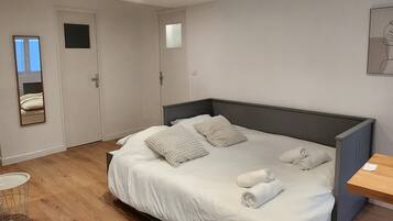 Une chambre à coucher moderne avec un grand lit, une table de chevet, un miroir et une petite table ronde.