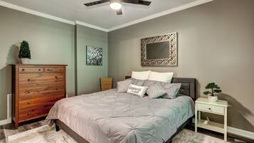 Un dormitorio con cama, cómoda, mesita de noche, ventilador de techo y decoración en la pared.