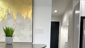 Een moderne keuken met een ronde tafel, een potplant en een groot abstract schilderij aan de muur.