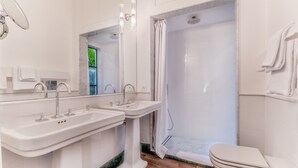 Une salle de bain avec deux lavabos, des toilettes et une douche.