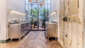 Une cuisine moderne dotée d’appareils électroménagers en acier inoxydable, d’un parquet en bois disposé en chevrons et offrant une vue sur un jardin grâce à des portes vitrées.
