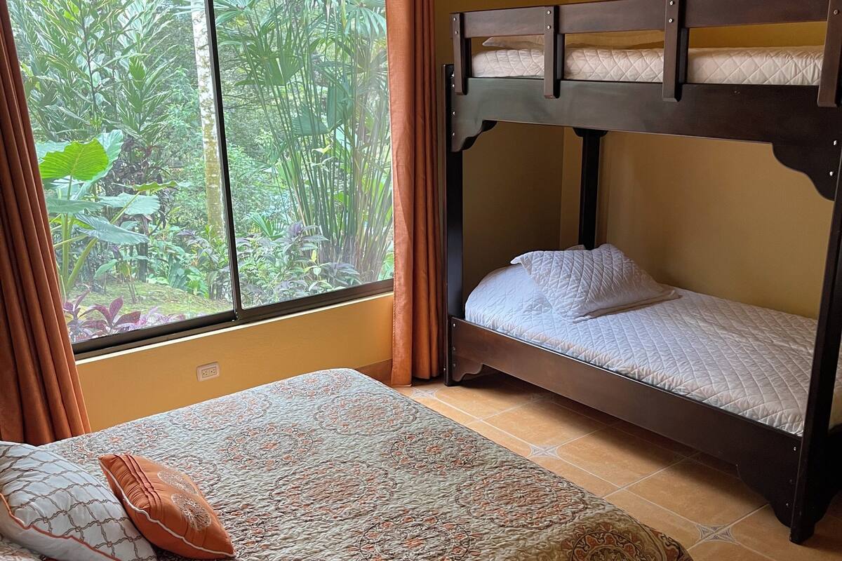 Una habitación con una cama litera y una cama individual, ambas con ropa de cama estampada.