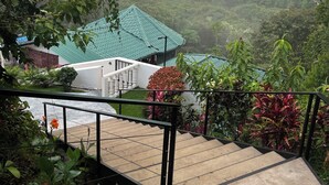 A staircase leading to a building with a green roof, surrounded by lush greenery and a mountainous backdrop. - The Mango Tree Villas and Spa (Ciudad Cortés)