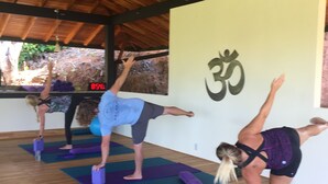 A yoga studio with wooden beams on the ceiling and a large wall with a symbol. - The Mango Tree Villas and Spa (Ciudad Cortés)