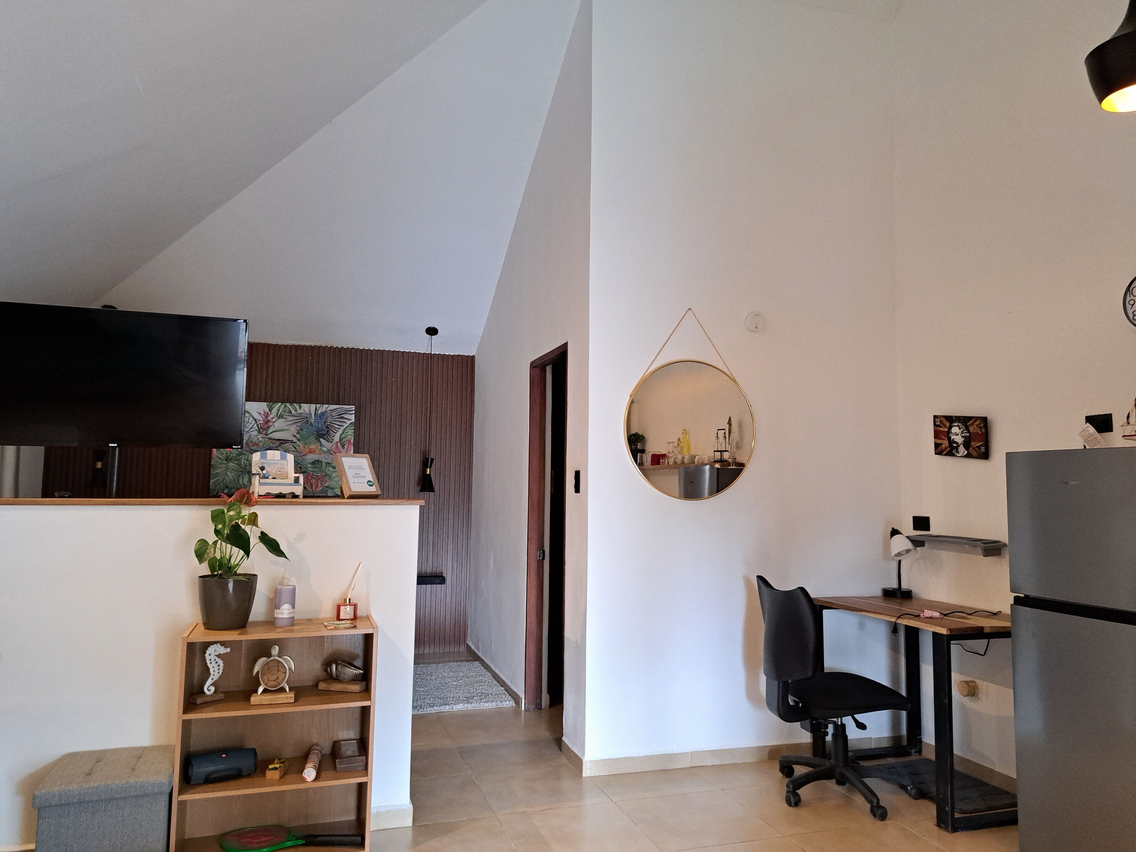 Una cocina moderna con comedor, un espejo redondo y un televisor en la pared.